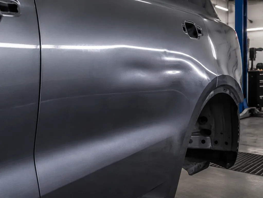 Rear quarter before repair: distorted body line, crown, and uneven surface